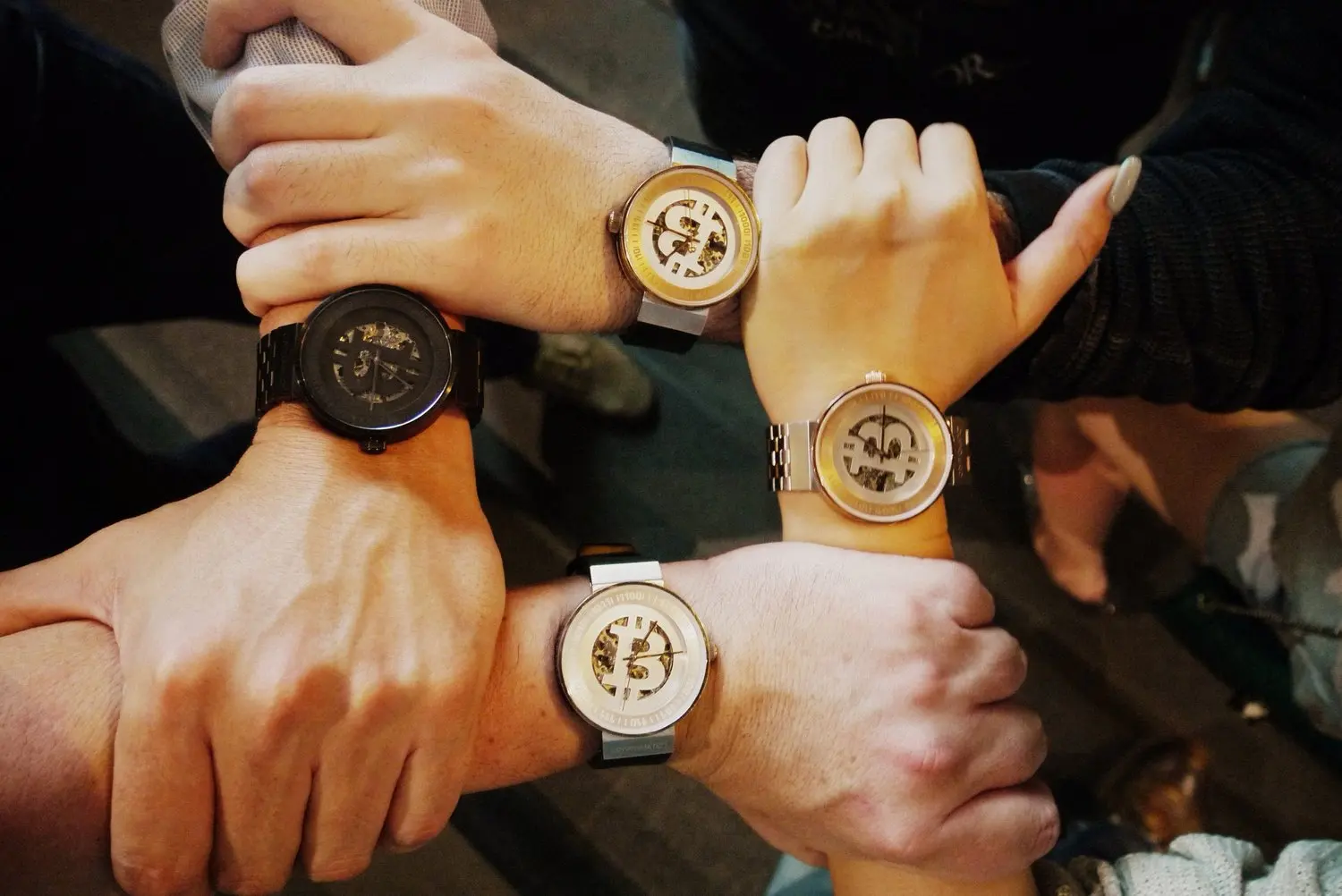 Five people showing their wrists with different watches, forming a circle with their hands.
