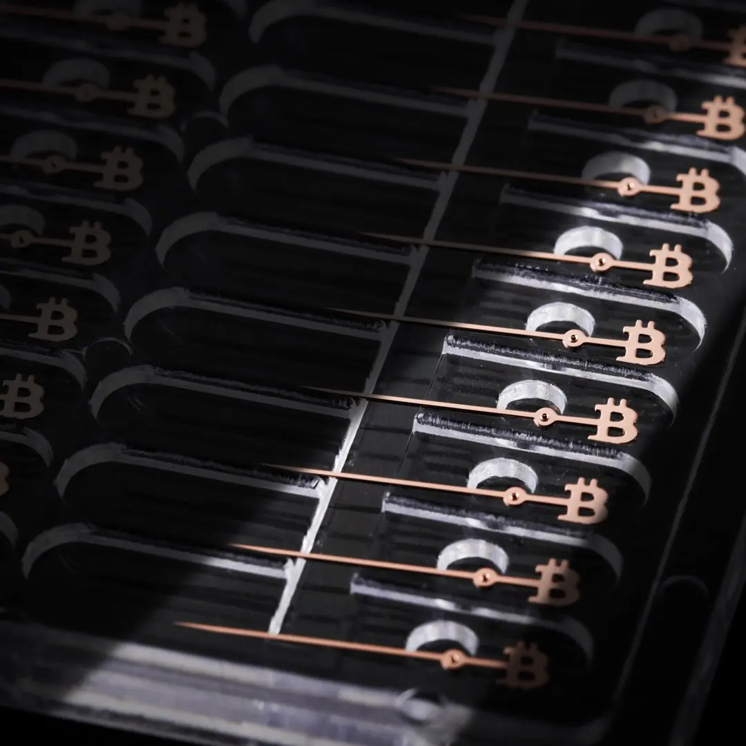 Close-up of a computer chip with Bitcoin symbols and copper wiring.