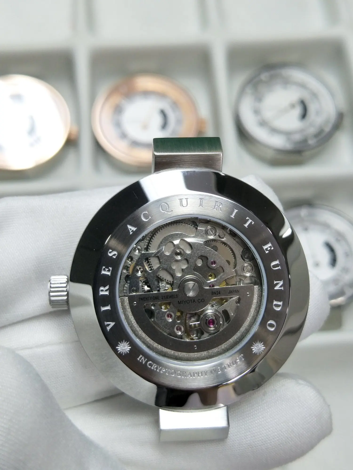 Close-up view of a silver bitcoin wristwatch with an open back displaying the internal gears and mechanics.